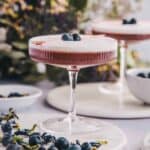 Blueberry gin sour in a glass with blueberry garnish.