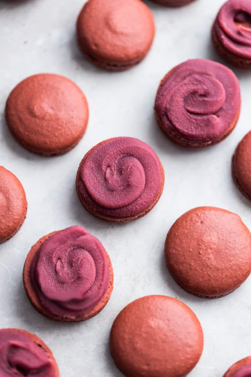 Filled raspberry macaron shells with raspberry yuzu ganache.