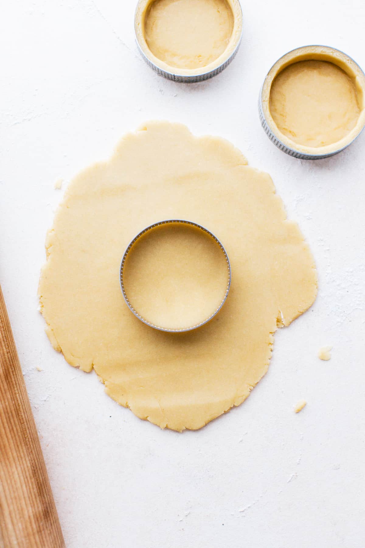 Rolling out and molding tart dough in mini tart rings.