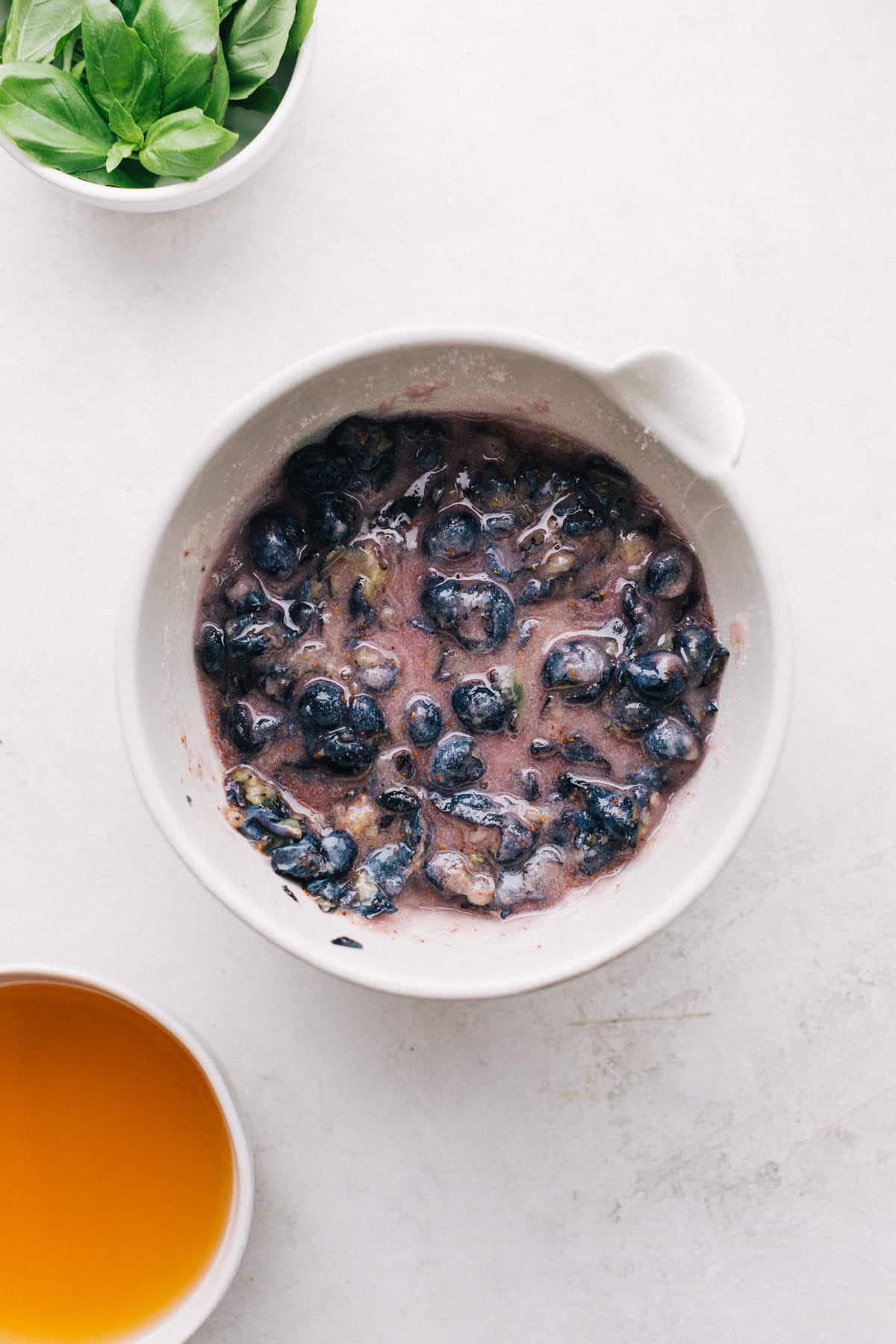 Muddled Blueberries in a bowl with sugar and basil.