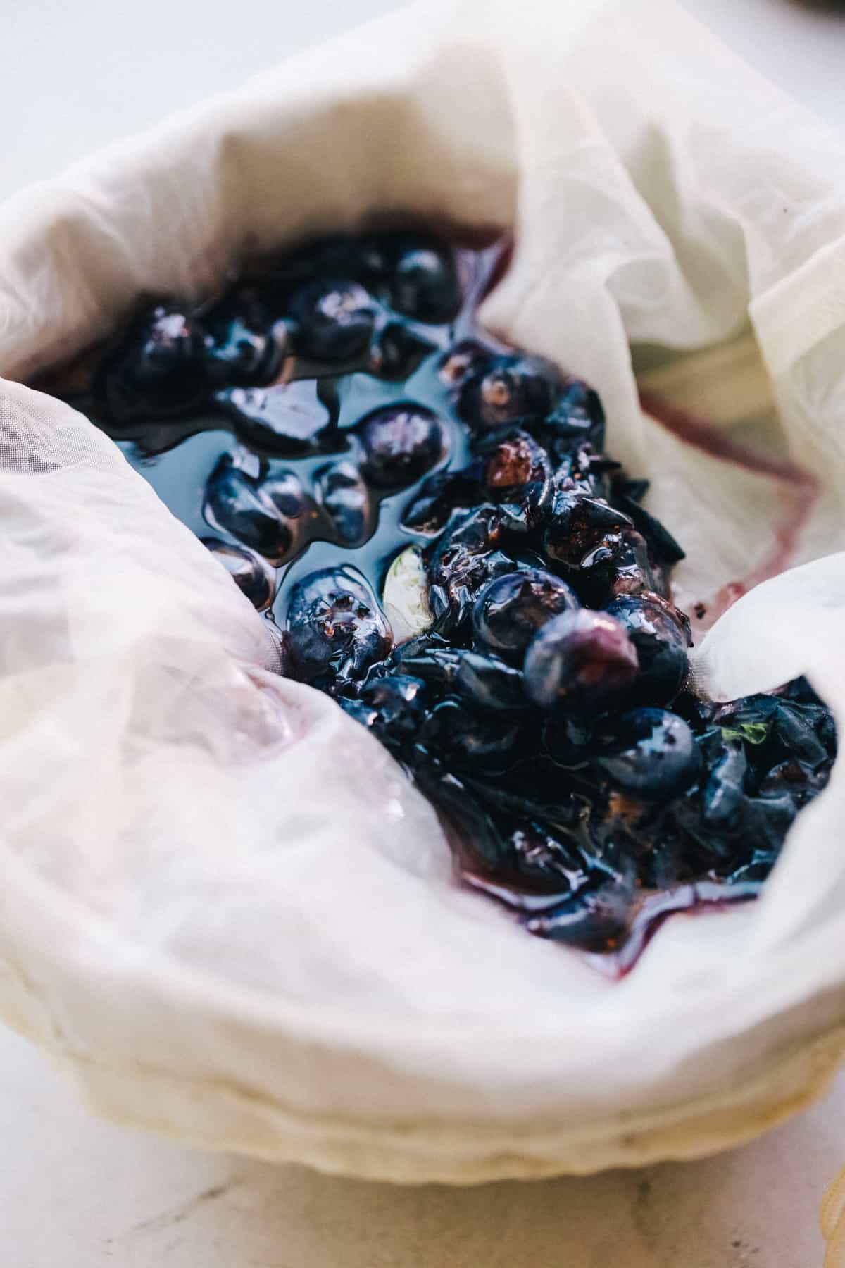 Squeezing out blueberry and basil juice using a cheese cloth.