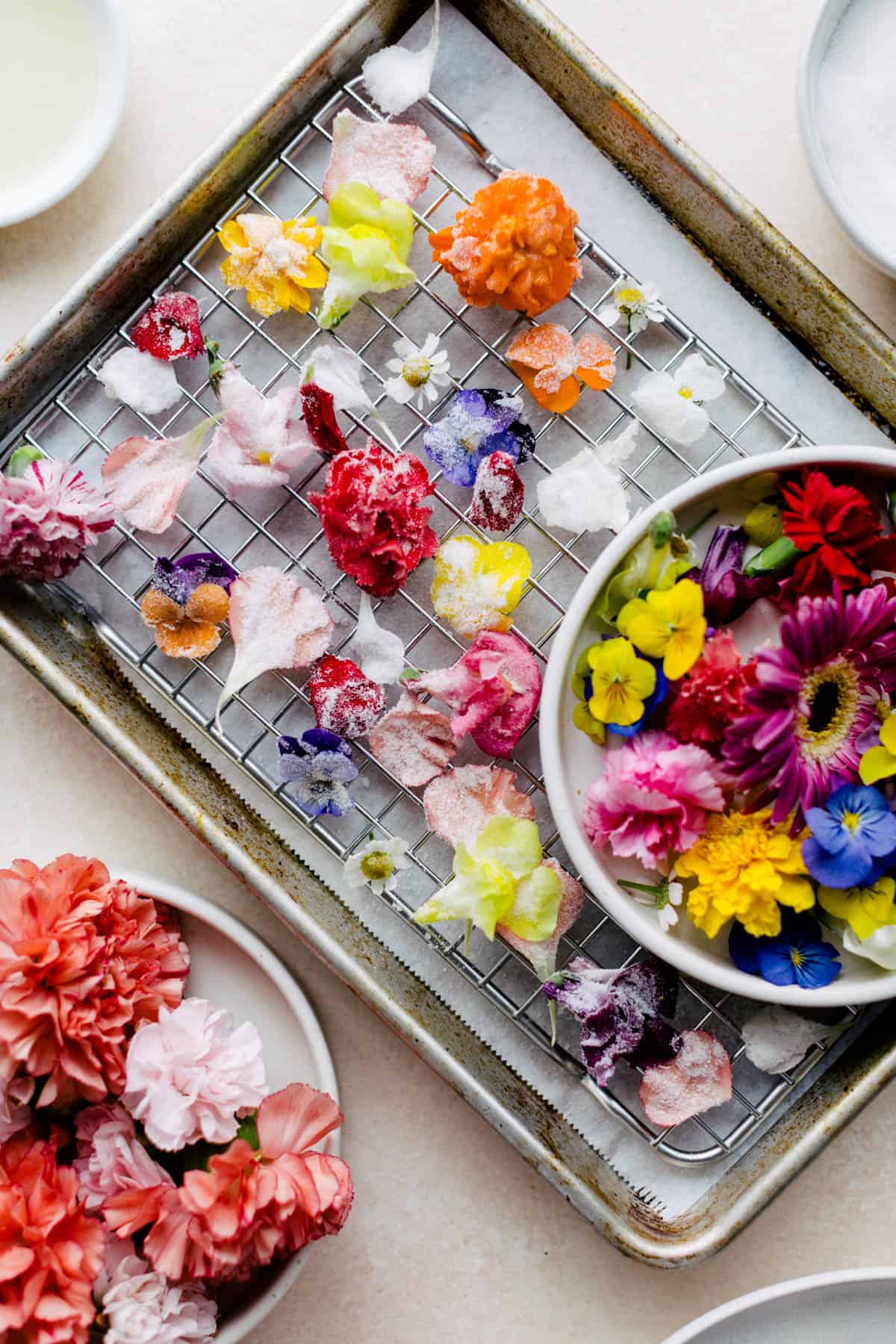 Candied flowers drying on parchment paper.