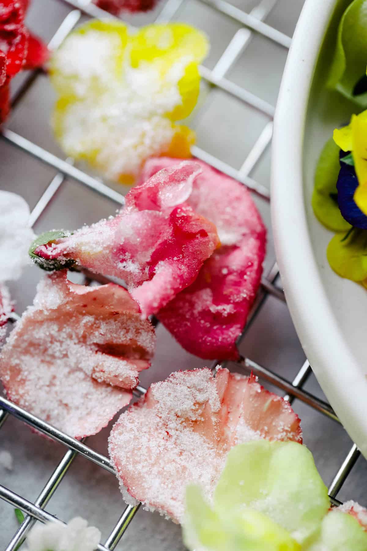 Sugared snapdragons and carnations on a wire rack.