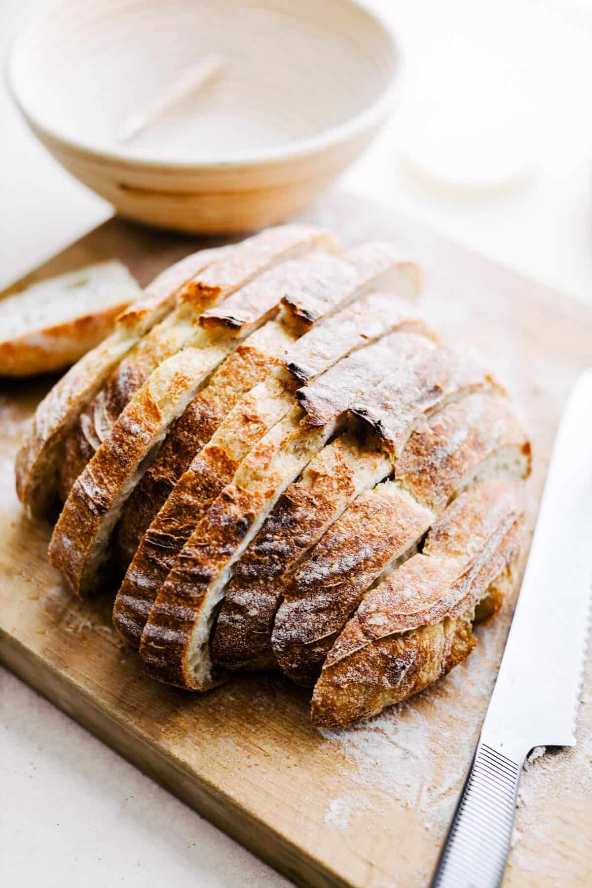Sourdough loaf cut into slices on cutting board.