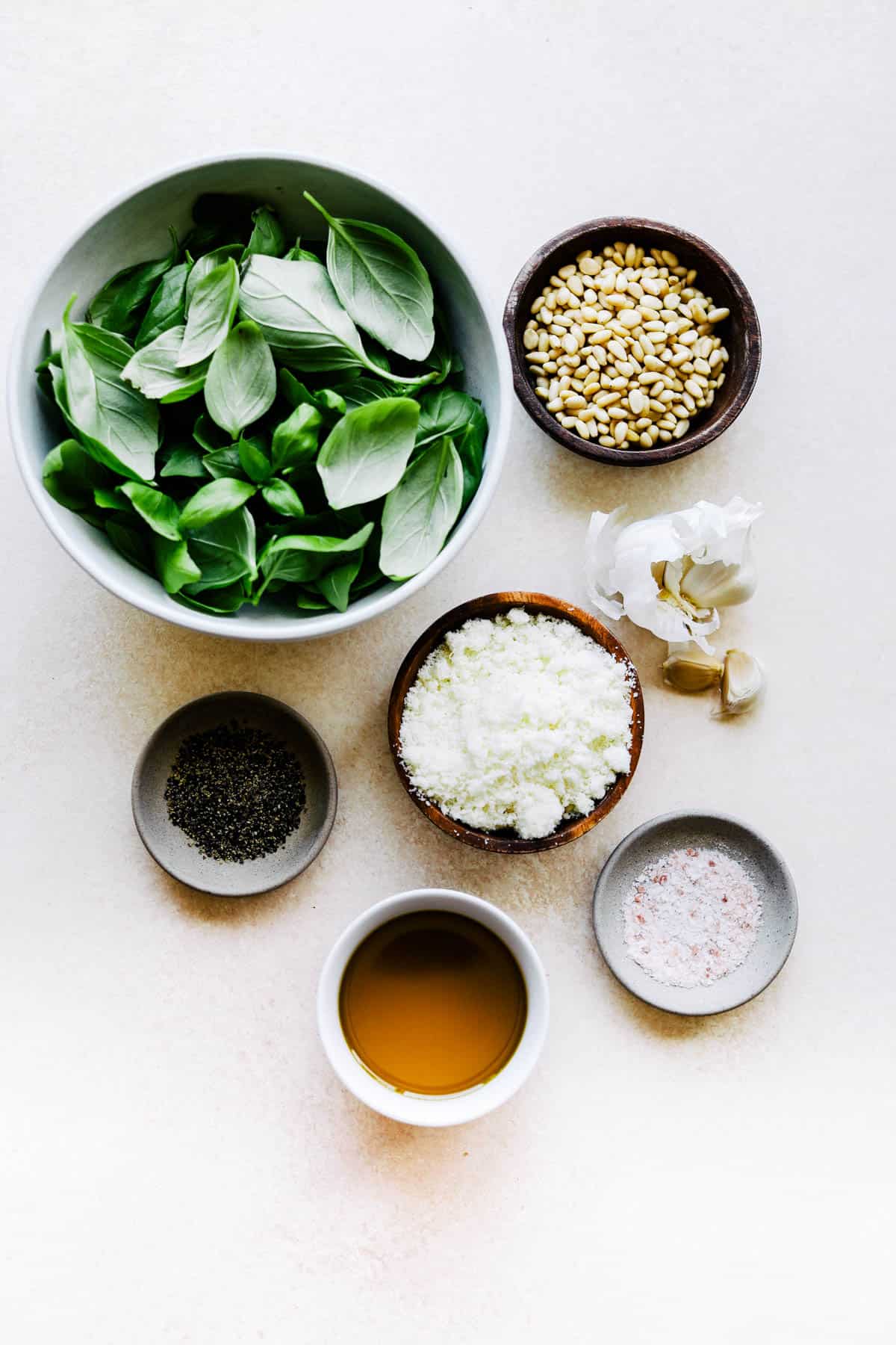 Ingredients needed to make pesto in small bowls.