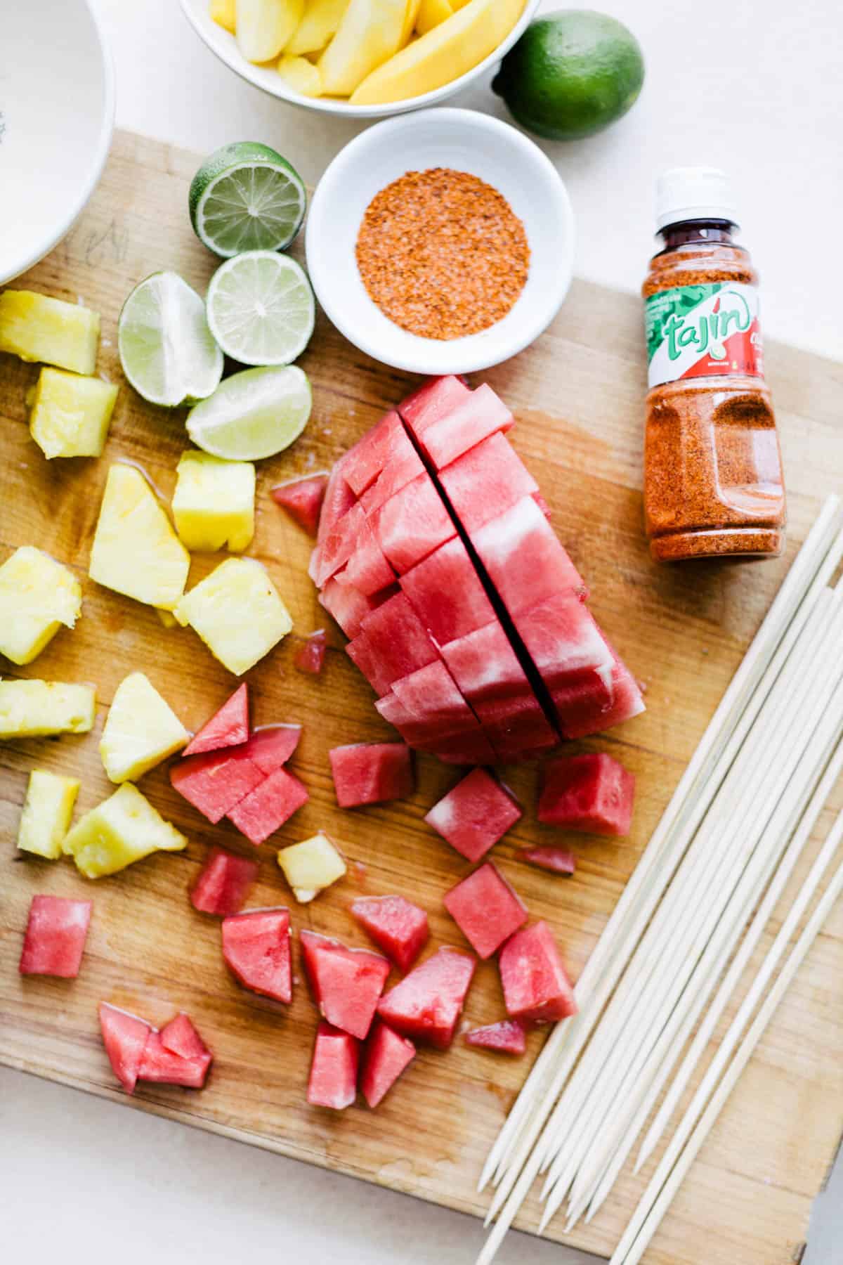 Cutting watermelon and fruit into cubes before adding tajin.