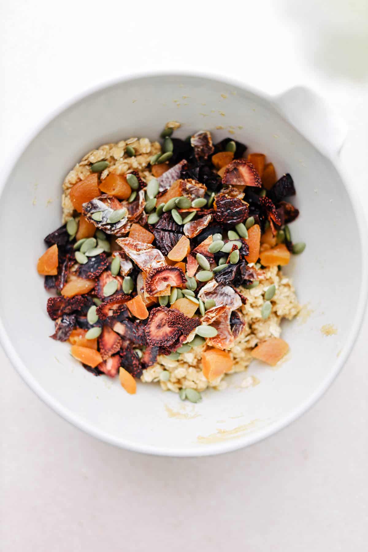 Adding dried fruits and nuts into a mixing bowl to make cookie dough.