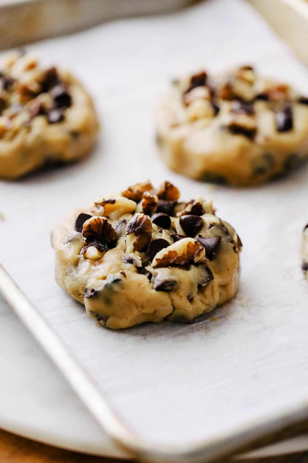 Scooped cookie dough on a parchment lined baking tray.