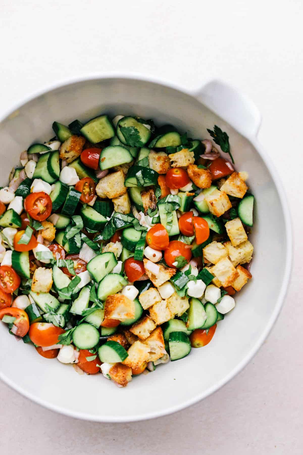 Mixed and tossed panzanella salad in a large bowl.