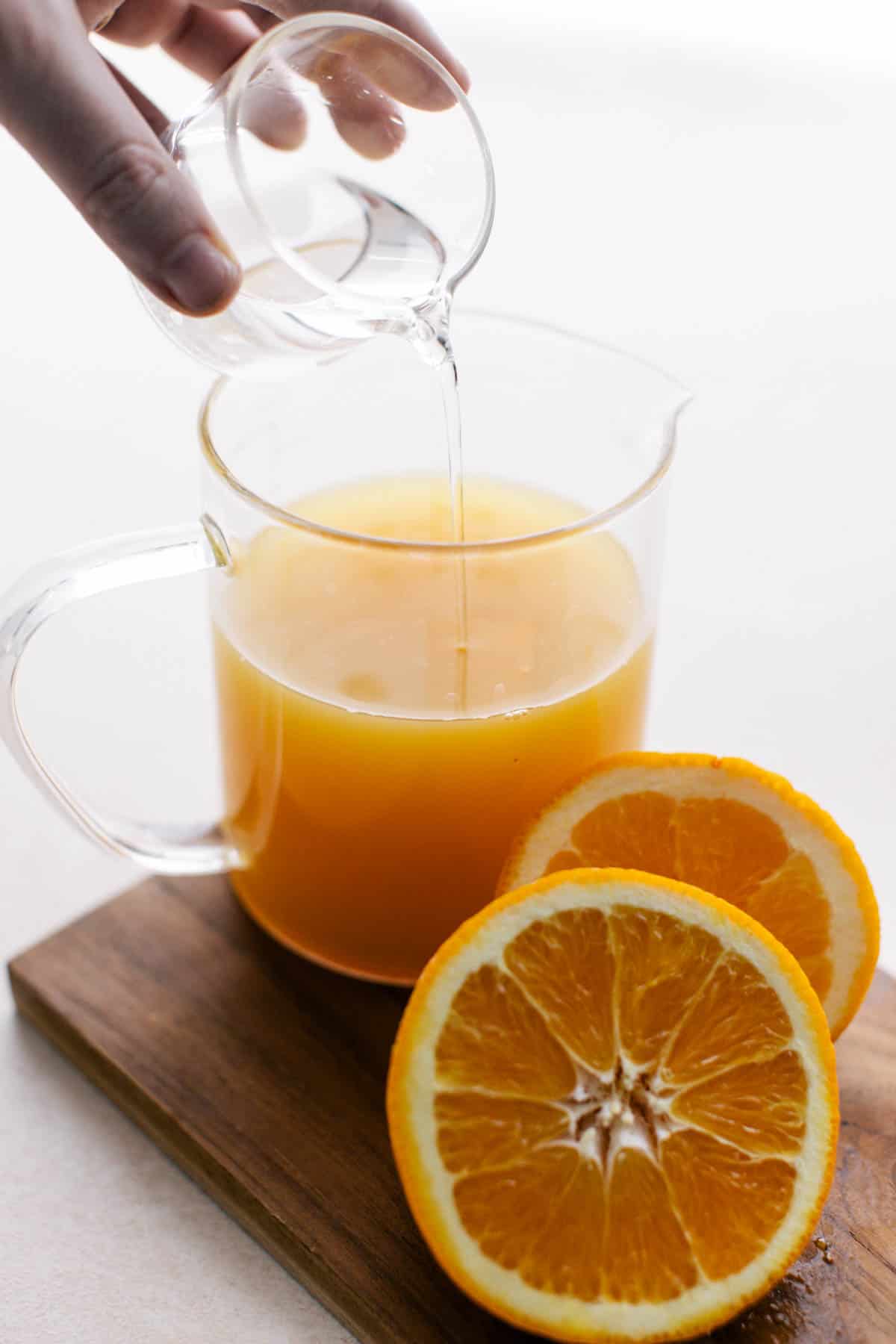 Pouring orange juice and vodka in a container.