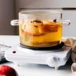 Simmer pot on a stove with apples and spices.