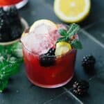 Blackberry bourbon smash with blackberry garnish in a glass.