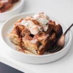 Brioche french toast casserole on a plate with whipped cream.