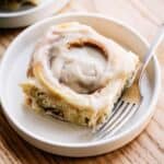 brown butter cinnamon roll on a plate with a fork.