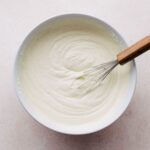 Creme legere in a bowl with a whisk nearby.