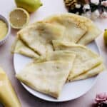 Parisian crepes on a plate with lemons and pastry cream nearby.