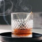 Smoked old fashioned cocktail in a glass with smoke.