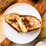 Sourdough grilled cheese sandwich sliced in half on a plate.