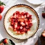 Tarte aux fraises on the counter with fresh strawberries and pastry cream on the tart.