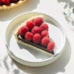 Slice of raspberry ganache tart on a plate.
