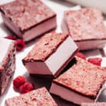 Raspberry ice cream sandwiches on the counter with fresh raspberries.