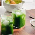 Matcha tonic in a glass cup with ice on the counter.