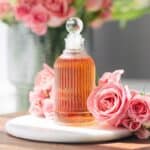 Rose simple syrup on the counter next to fresh roses.