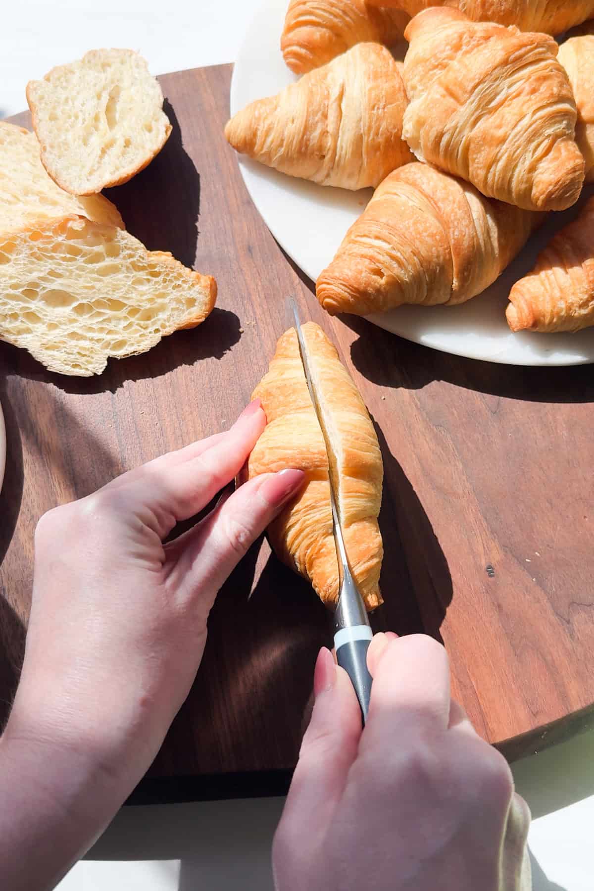 Slicing croissants in half on a cutting board. 
