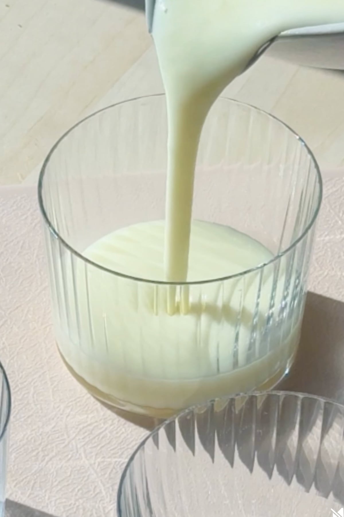 Pouring lemon posset into a cup to set.