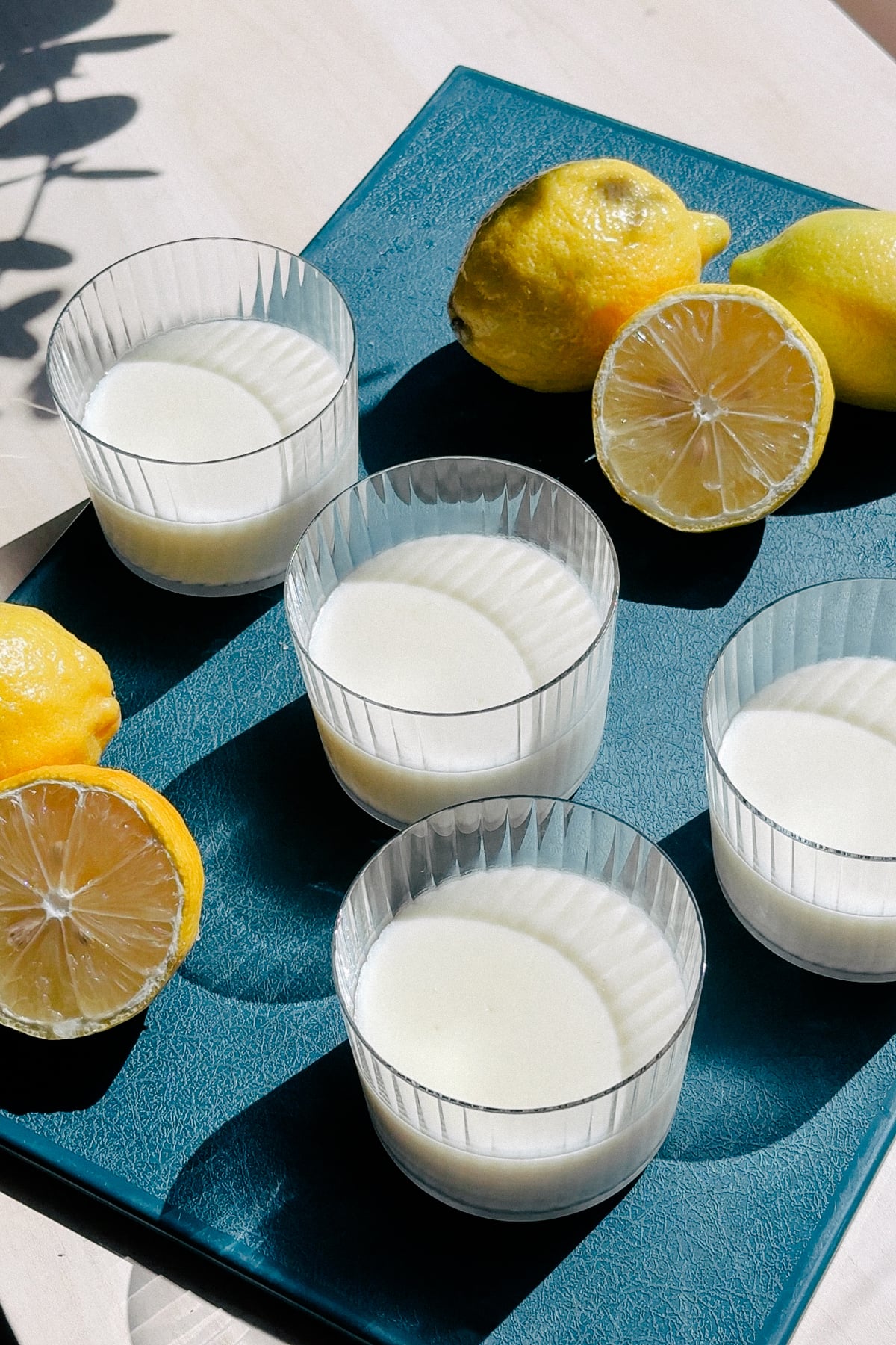 Serving glasses of lemon posset on a cutting board.