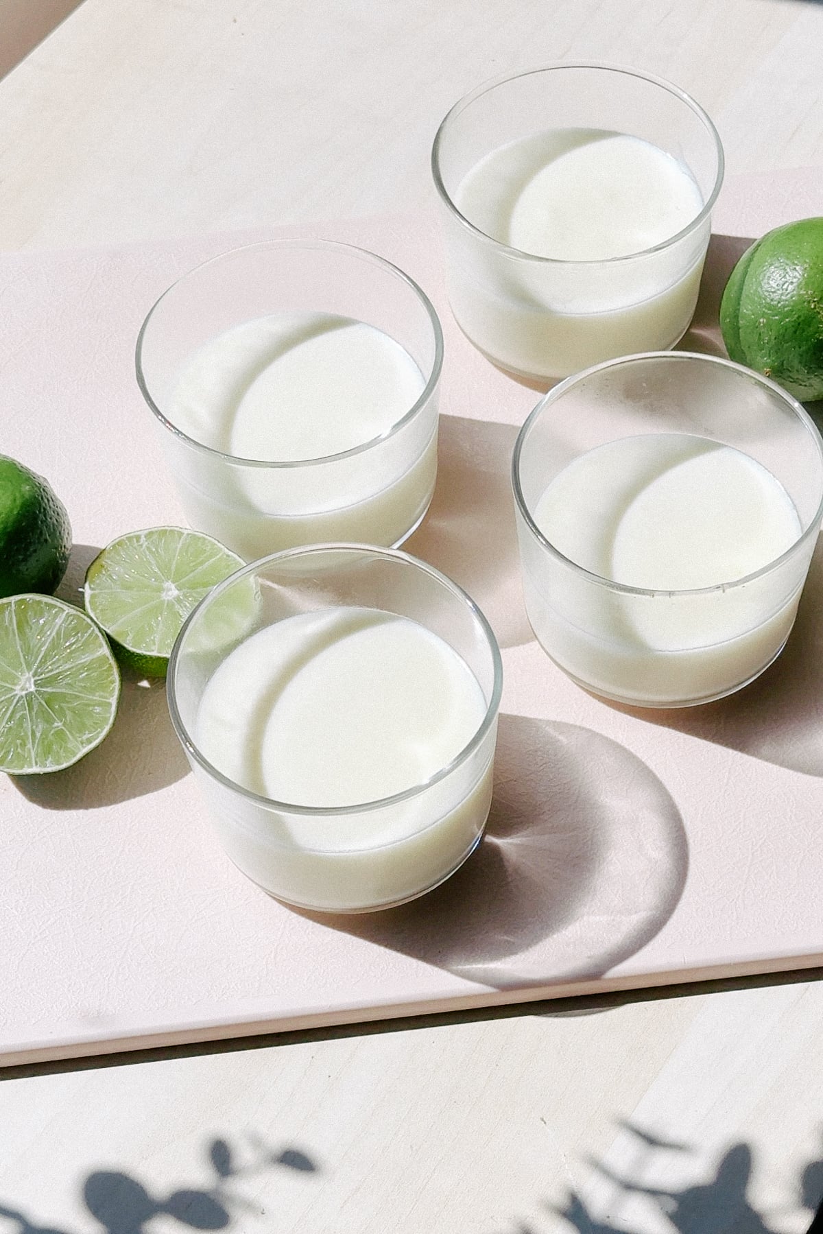 Serving glasses of lime posset on a cutting board.