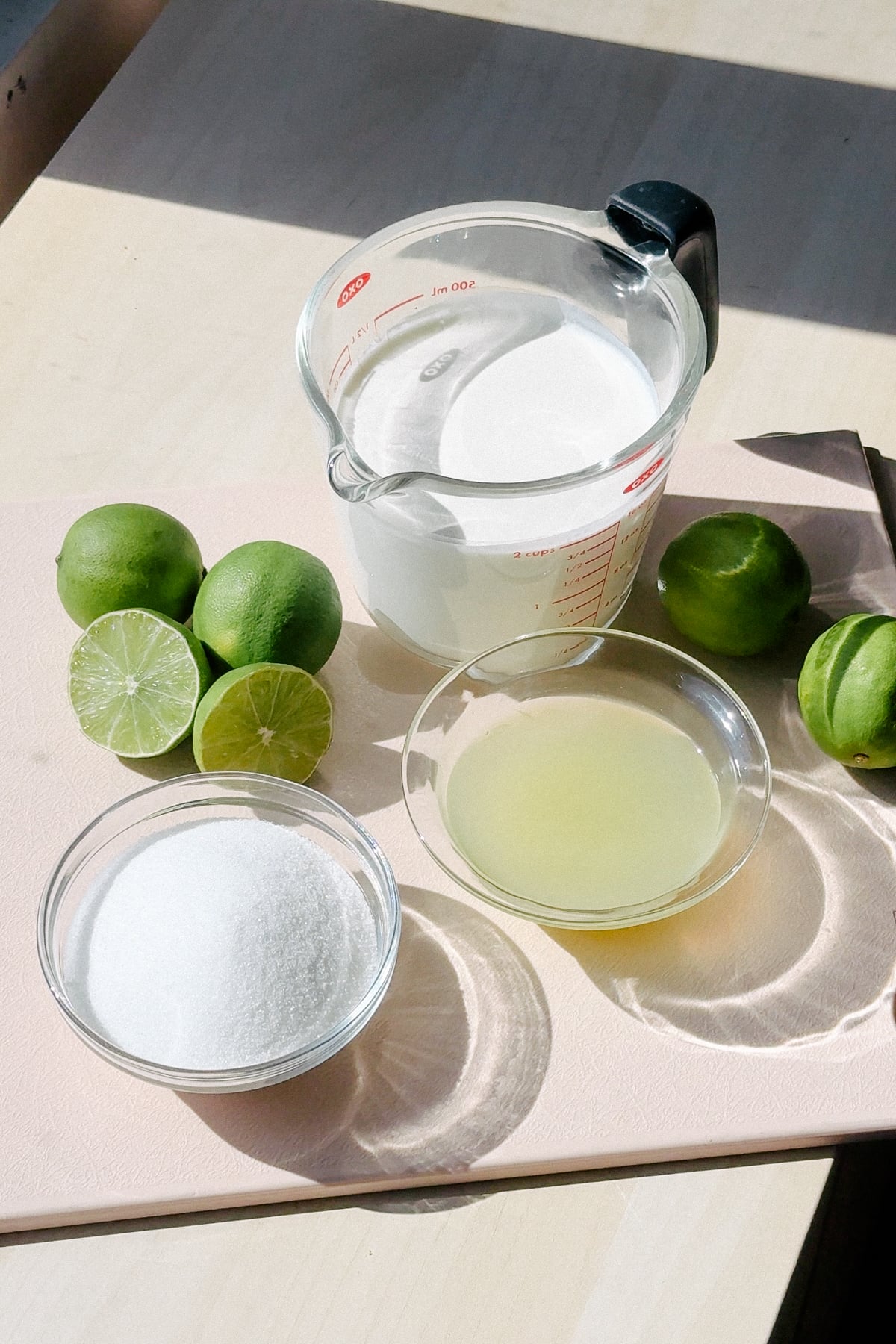 Ingredients needed to make a lime posset on a cutting board.