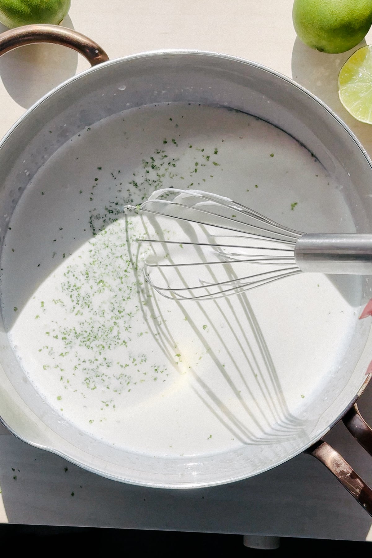 Infusing cream and sugar with lime zest in a saucepan.