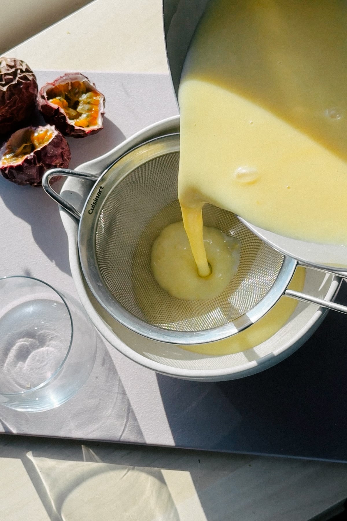 Straining passion fruit posset through a sieve. 