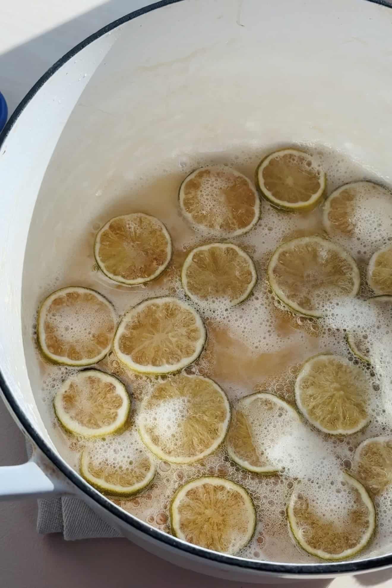 Limes simmering in simple syrup in a dutch oven.