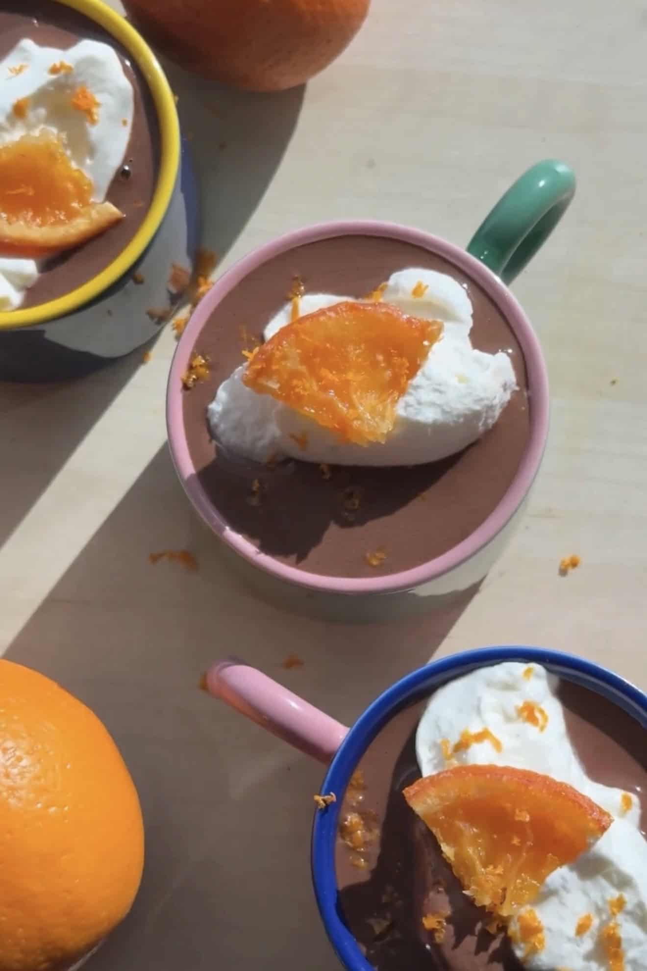 overhead French hot chocolate with softly whipped cream and a candied orange in a ping mug.