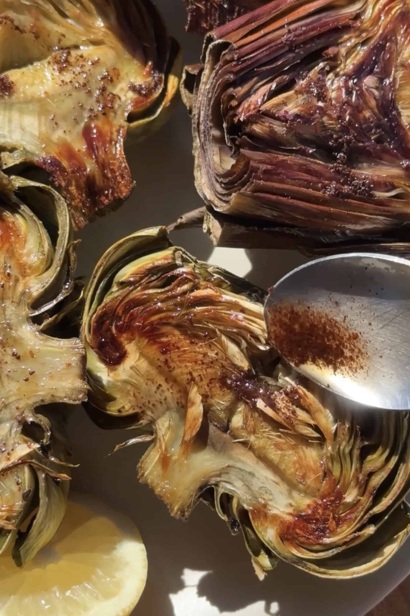 Spooning brown butter into roasted artichokes.