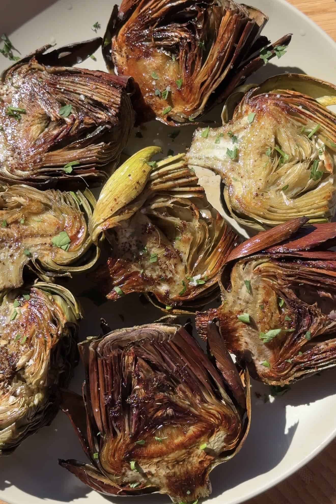 Plated roasted artichokes that have been garnished.