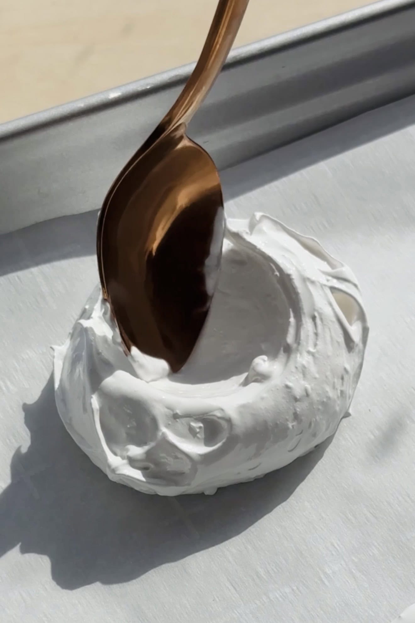 Using a spoon to form the mini pavlova nests.