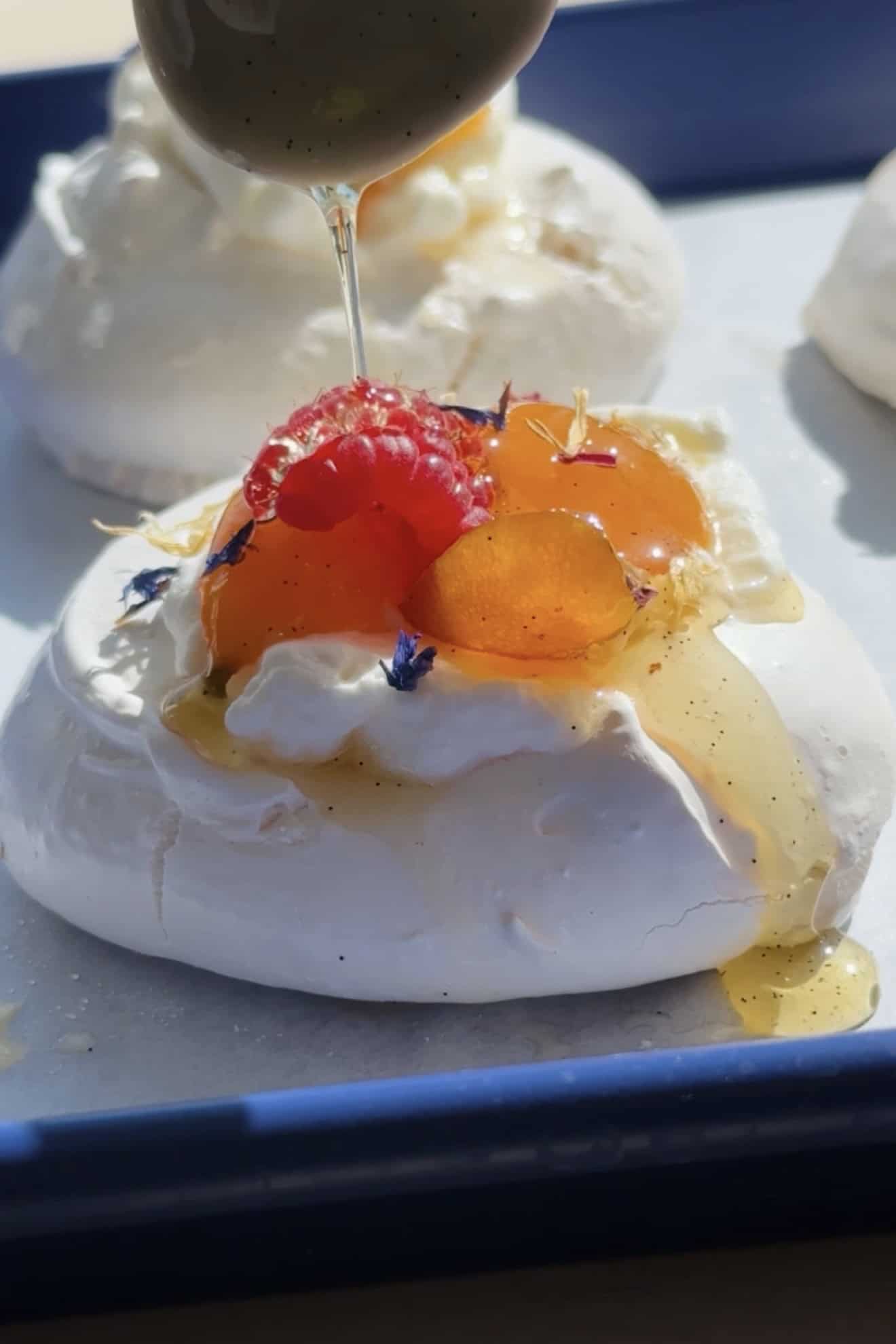 Close up candied Kumquat Pavlova Nest on a baking sheet with syrup spooned on.